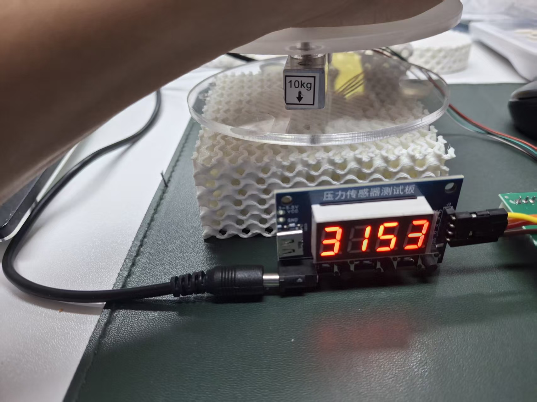 Lattice sample beneath an acrylic compression plate with a force sensor and digital display